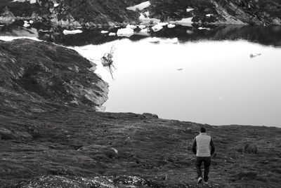 Man walking alone towards river in winter