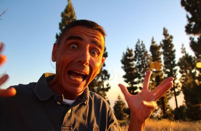 Portrait of mature man screaming while standing against clear sky during sunset