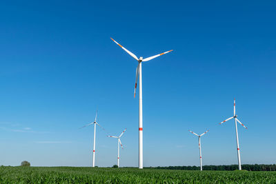 Five wind power turbines, part of a wind farm, on a green field near cottbus, brandenburg, germany.