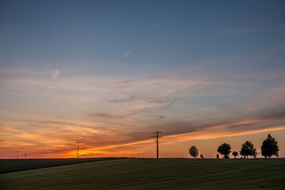 Silhouette trees on field against sky during sunset