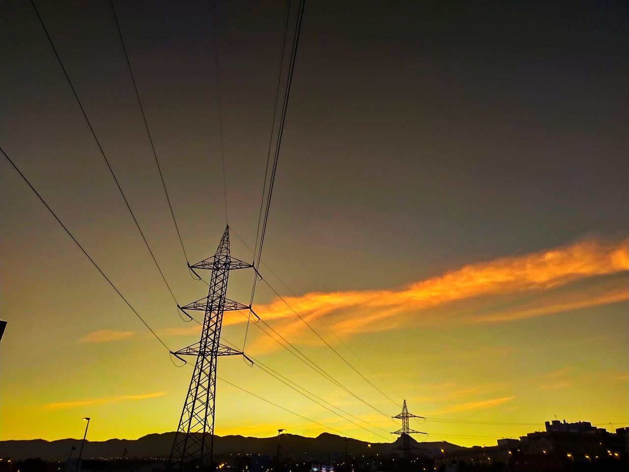 LOW ANGLE VIEW OF SILHOUETTE ELECTRICITY PYLONS AGAINST DRAMATIC SKY