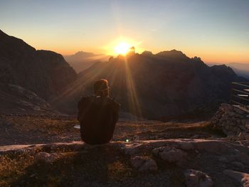 Man on rock against sky during sunset