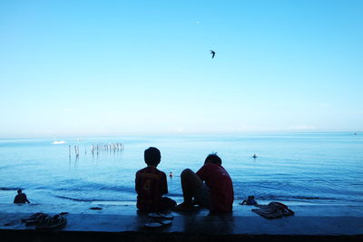 People on beach against clear sky