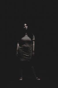Woman standing against black background