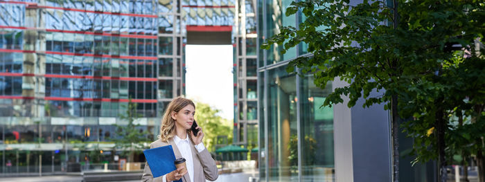 Portrait of young woman standing against building