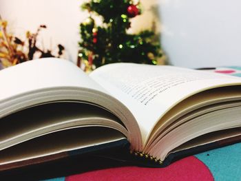 Close-up of book against christmas tree at home