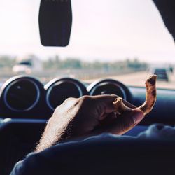 Close-up of woman hand holding car against sky