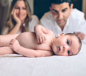 Portrait of cute baby girl lying on bed