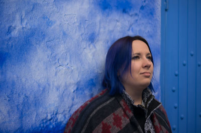 Thoughtful woman against blue wall