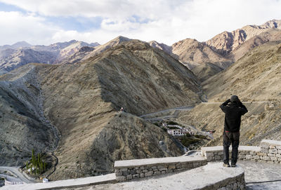 Rear view of man standing on rocky mountain