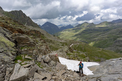 Rear view of person walking on mountain against sky