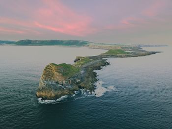 Rock formations amidst sea against sky during sunset