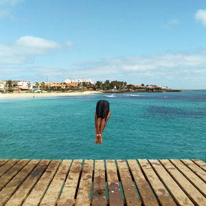 Rear view of man looking at sea against sky