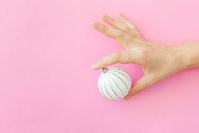 Close-up of hand holding apple against pink background
