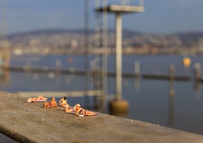 Miniature figures sunbathing on pier by sea against sky