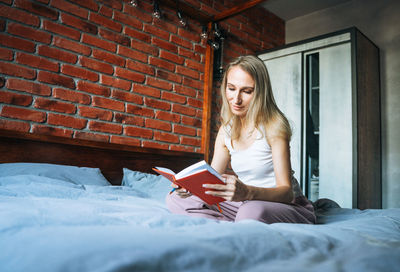 Young adult woman forty years writes notes in planner on bed at home