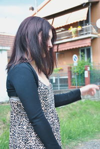 Side view of woman standing against built structure