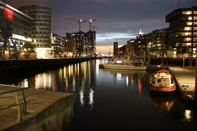 Boat moored in river against illuminated buildings