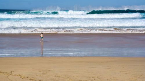 Boy standing on beach against sky