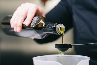 Cropped image of person pouring oil from bottle