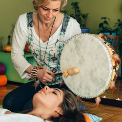 Therapist playing drum by young woman at spa