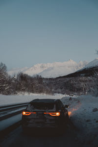 Car on road against snowcapped mountains during winter