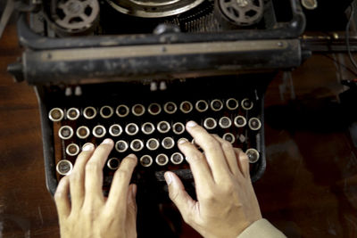 Cropped hands of person typing on vintage typewriter at table