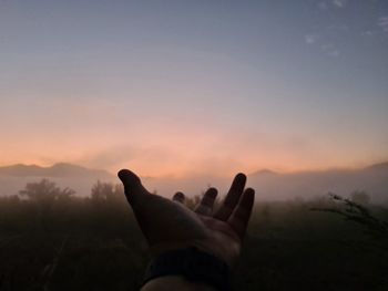 Midsection of person against sky during sunset