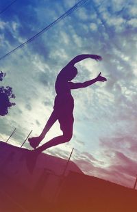 Low angle view of person jumping against sky