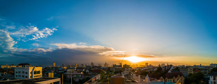 Cityscape against cloudy sky at sunset