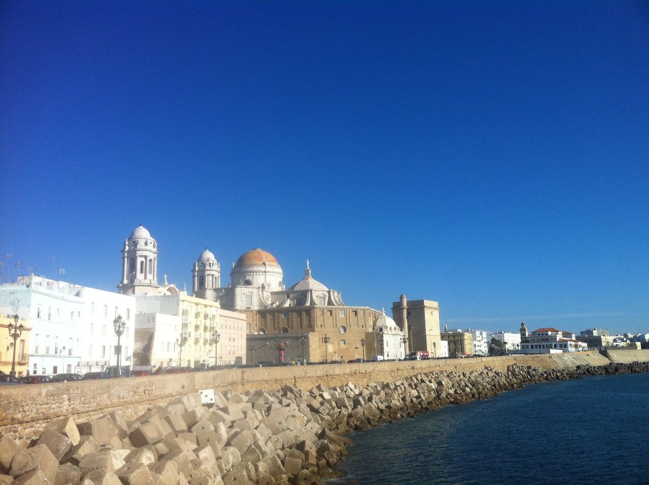 clear sky, architecture, built structure, copy space, building exterior, blue, water, city, waterfront, travel destinations, day, cityscape, river, outdoors, sea, famous place, sunlight, no people, building, tourism