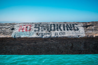 Graffiti on blue sea against clear sky