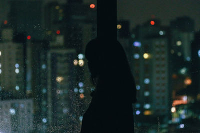 Woman looking through window at night