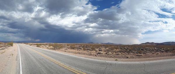 Road passing through desert against sky