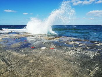 Waves splashing on shore against sky