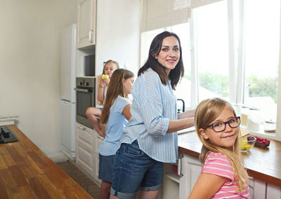 Portrait of mother with daughters working in kitchen