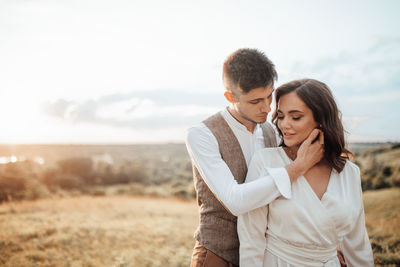 Young couple kissing against sky