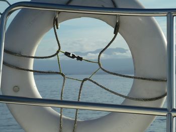 Close-up of railing against sea looking through life buoy