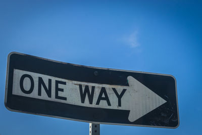 Low angle view of road sign against blue sky