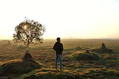 Rear view of man standing on field against sky