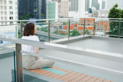 Solo asian woman during outdoor break and relax at rooftop with city background
