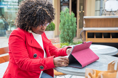 A young african american woman in a red coat cheking bill after shopping