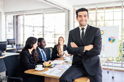 Portrait of businessman with colleagues in background in office