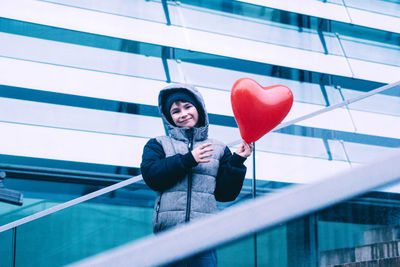 Full length portrait of young woman standing with balloon