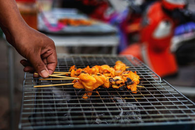 Close-up of man preparing food on barbecue grill