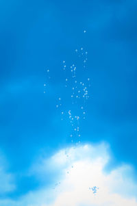 Low angle view of splashing water against blue sky