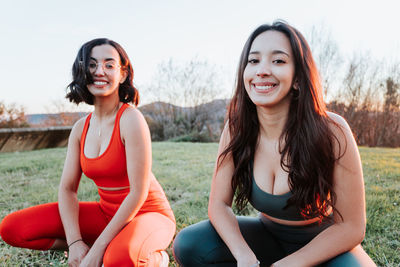 Portrait of smiling young females crouching at park
