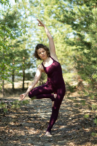 Full length of young woman jumping in forest