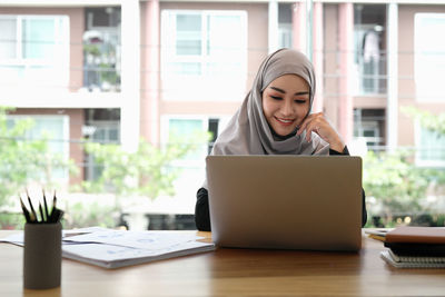 Portrait of young woman using laptop at table