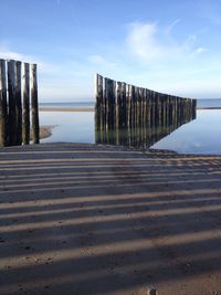 Wooden posts on beach against sky